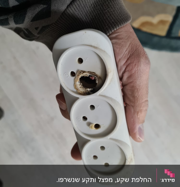 שקע חשמלי עם נזק בולט ביד אדם
